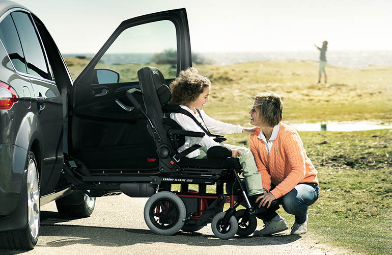 Woman interacting with a young girl who is sitting in an outward facing swivel seat in a black car