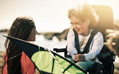 Woman and young girl smiling at each other on a sunny beach